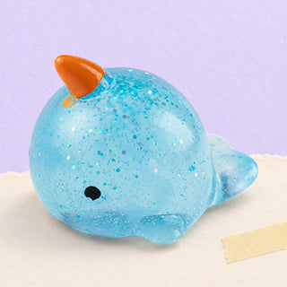 Narwhal squishy mochi – Mochi Squishy Narwhal with Glitter, product photo on pastel paper