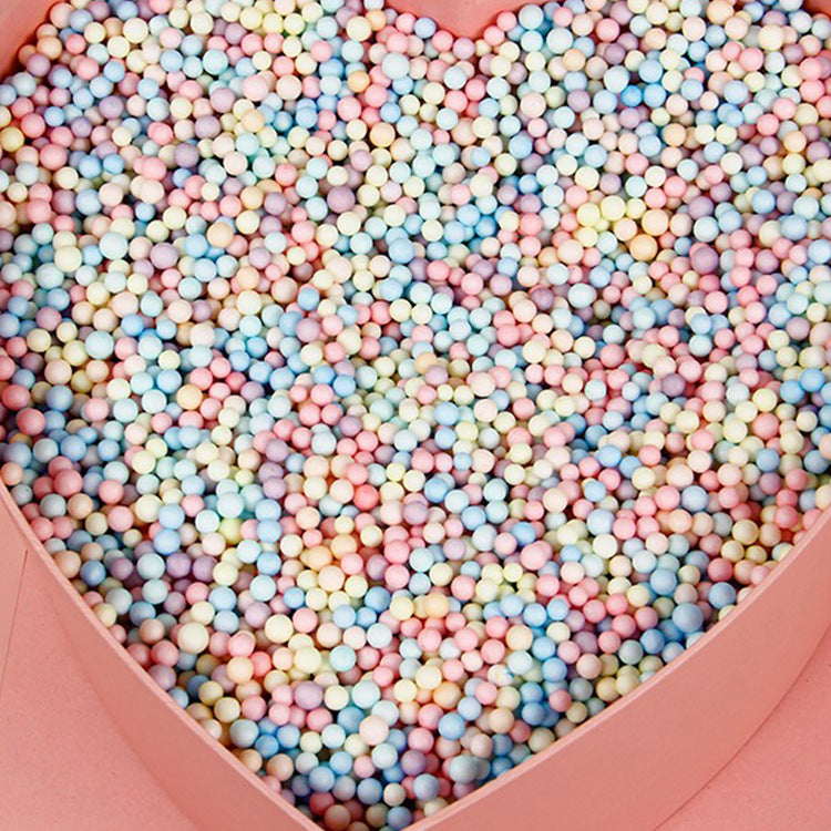 Pastel foam beads filling a pink heart shaped box