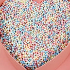 Pastel foam beads filling a pink heart shaped box