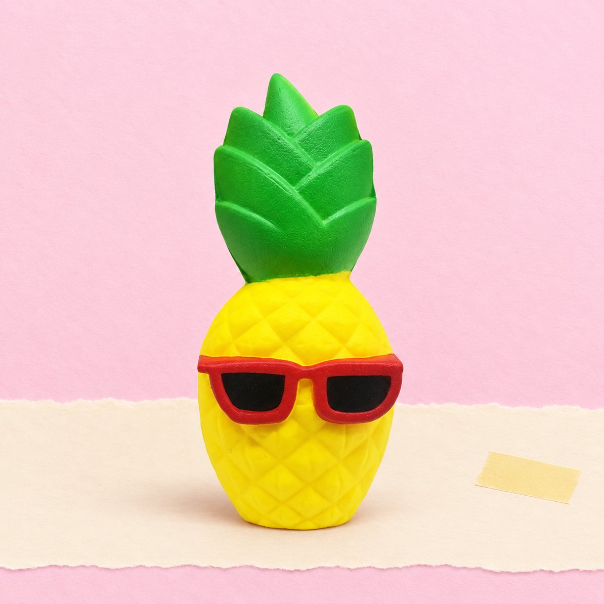 Ananas-squishy med solbriller, produktfoto på pastelfarvet papir