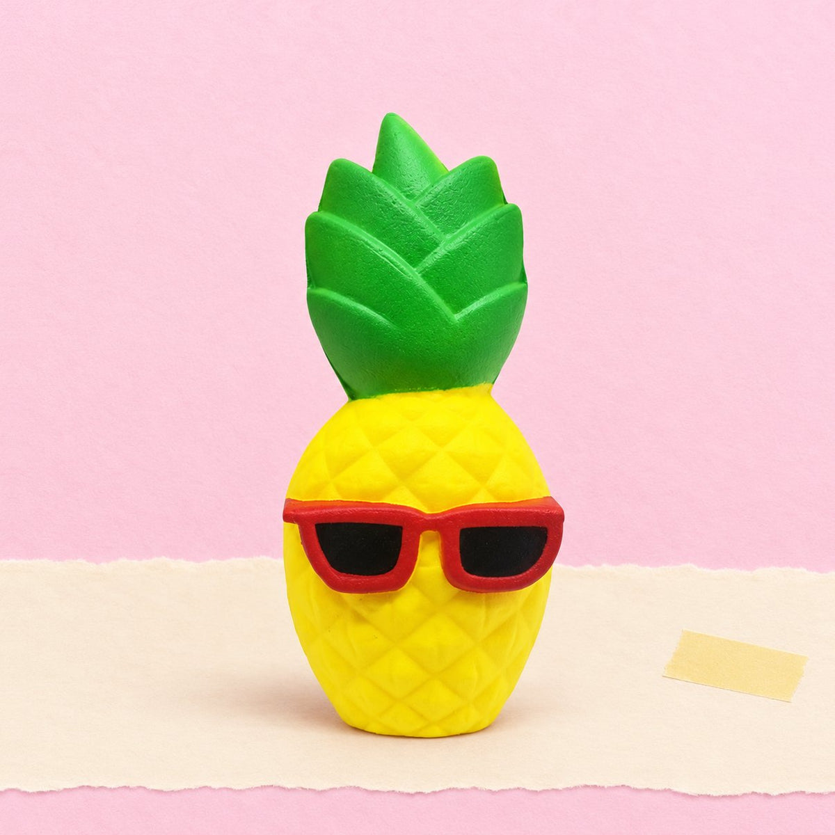 Ananas squishy met zonnebril op pastelkleurig papier