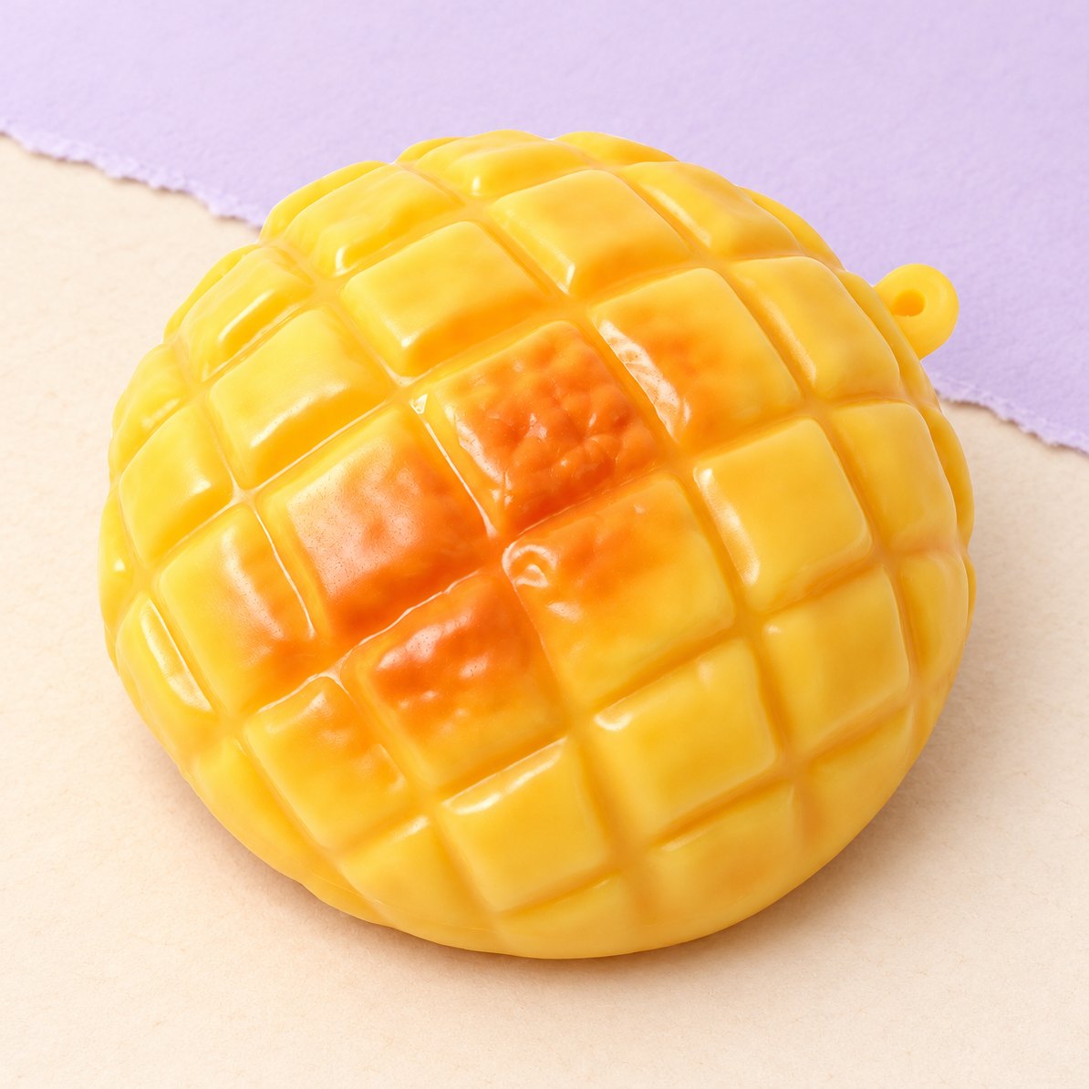 Ananasbolle-squishy på 9 cm med knas, produktfoto på pastelfarvet papir