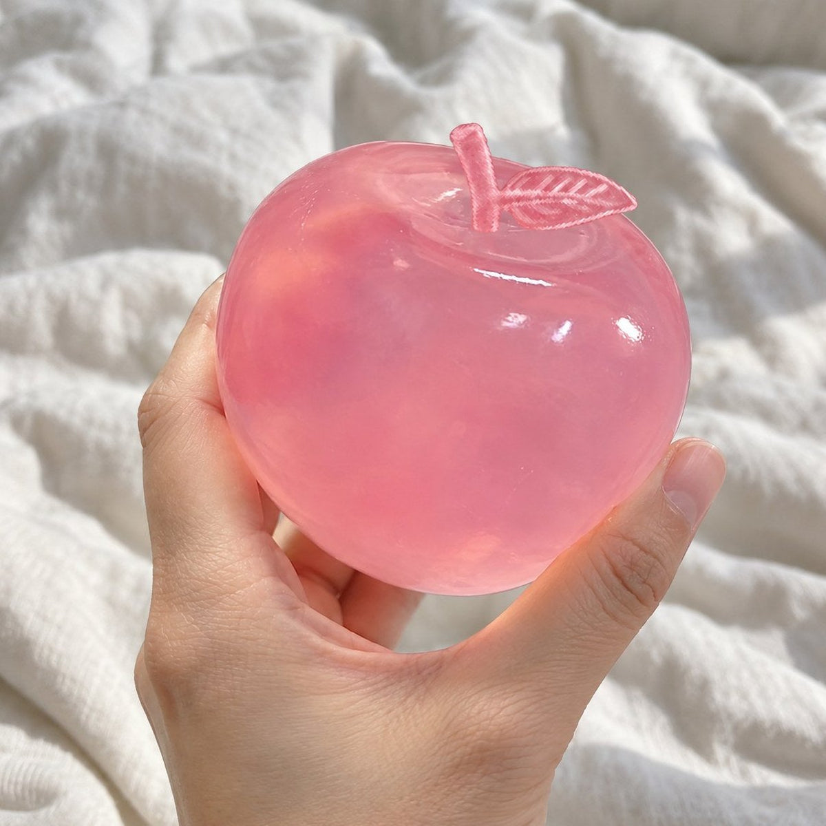 Rekbare appel squishy in poederroze, naar de camera gehouden in ik-perspectief