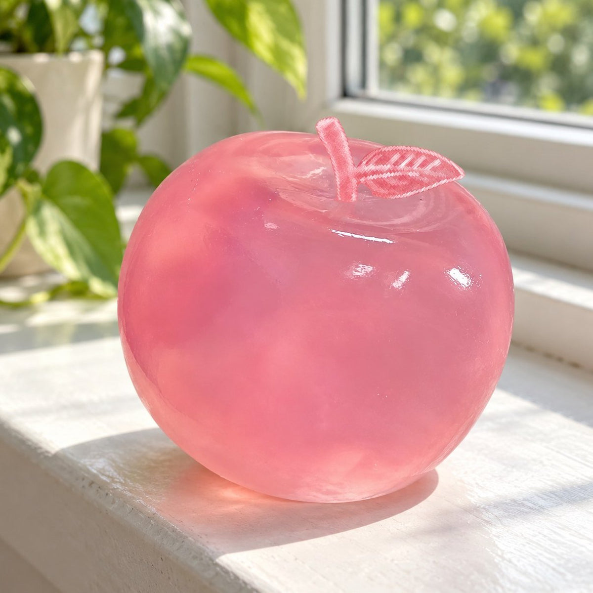 Rekbare appel squishy in poederroze op een zonnige vensterbank