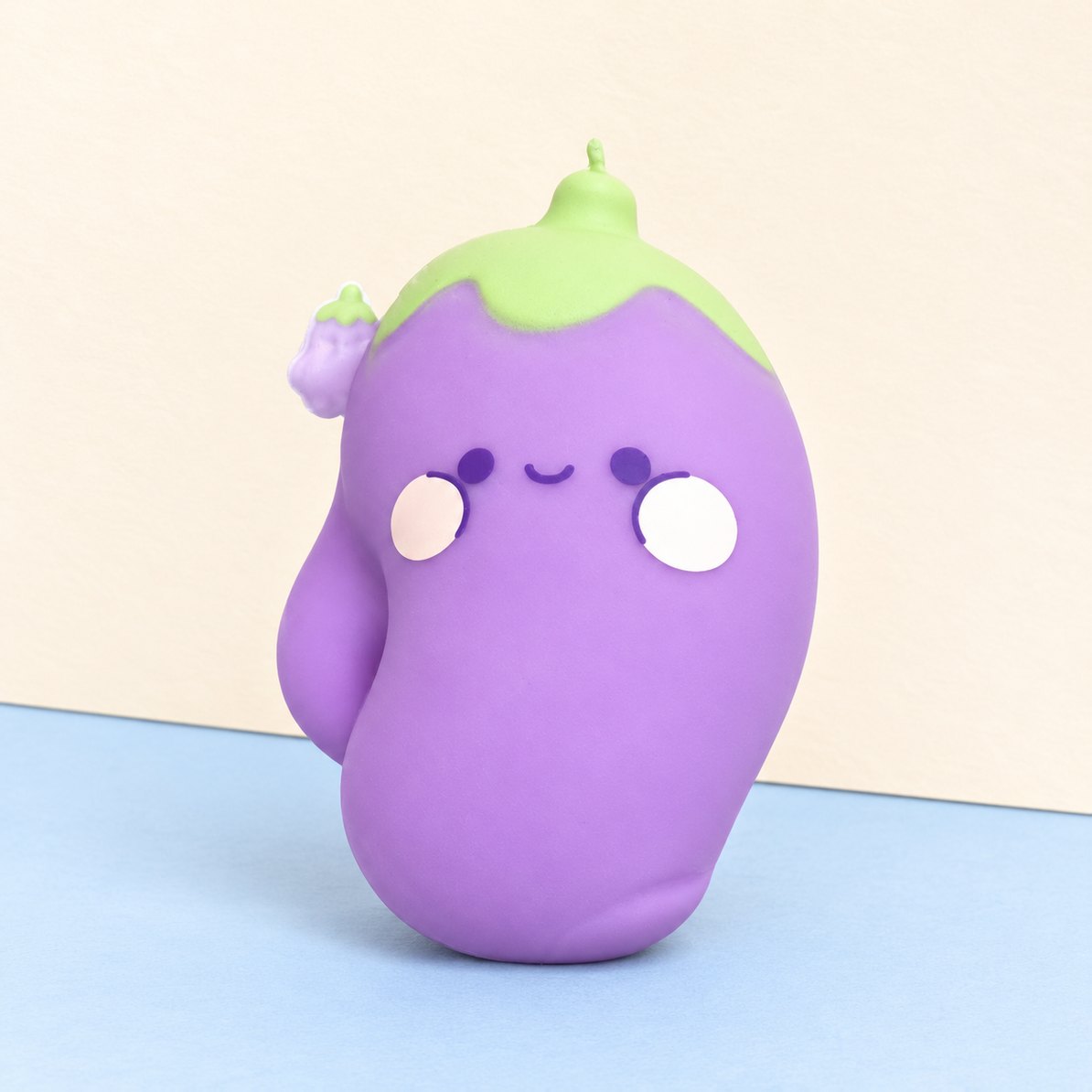 Kæmpe aubergine squishy med kawaii-ansigt på pastelfarvet papir