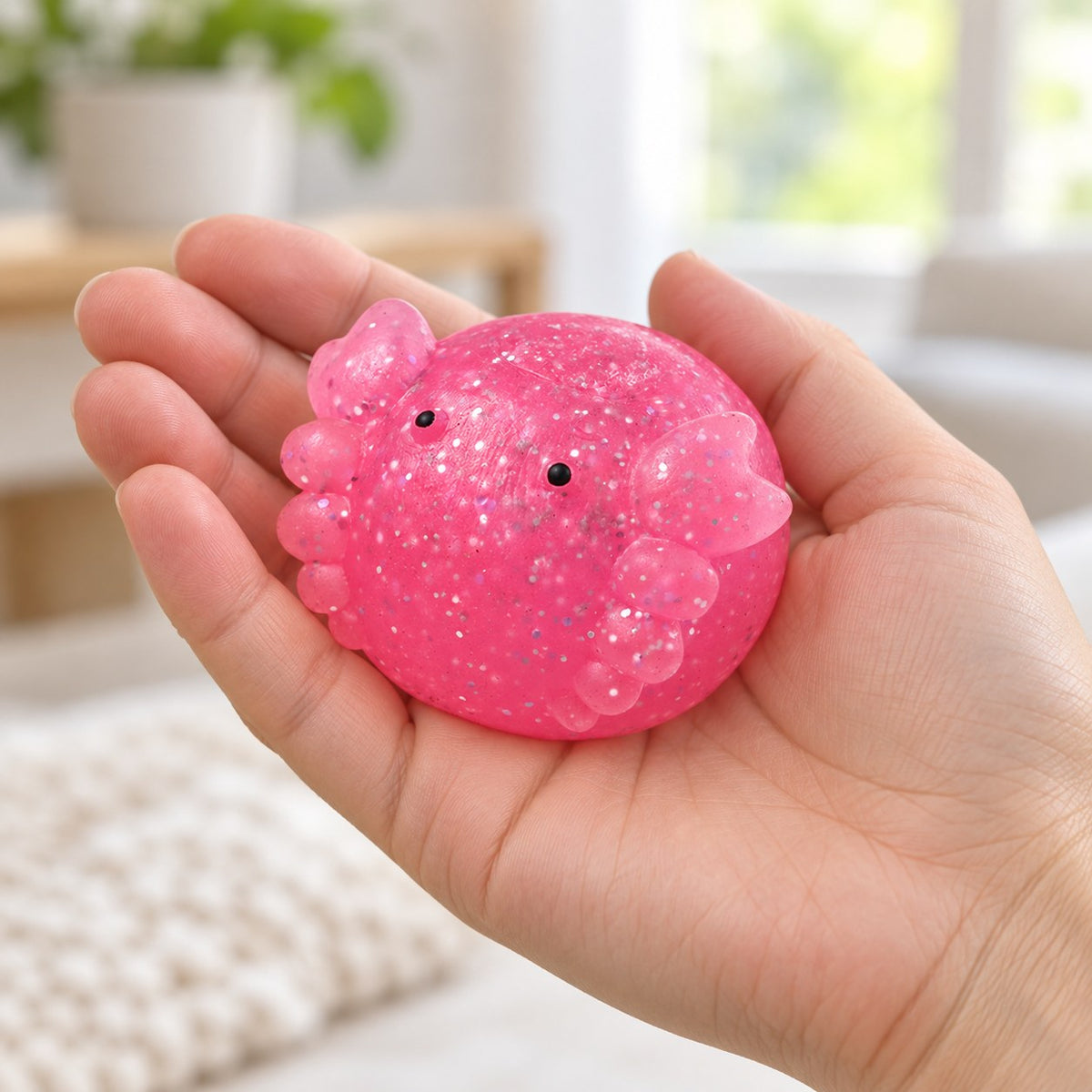 Axolotl Mochi Squishy with Glitter, held in a hand to show the real size