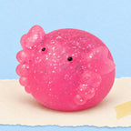 Axolotl squishy mochi glitter – Axolotl Mochi Squishy with Glitter, product photo on pastel paper