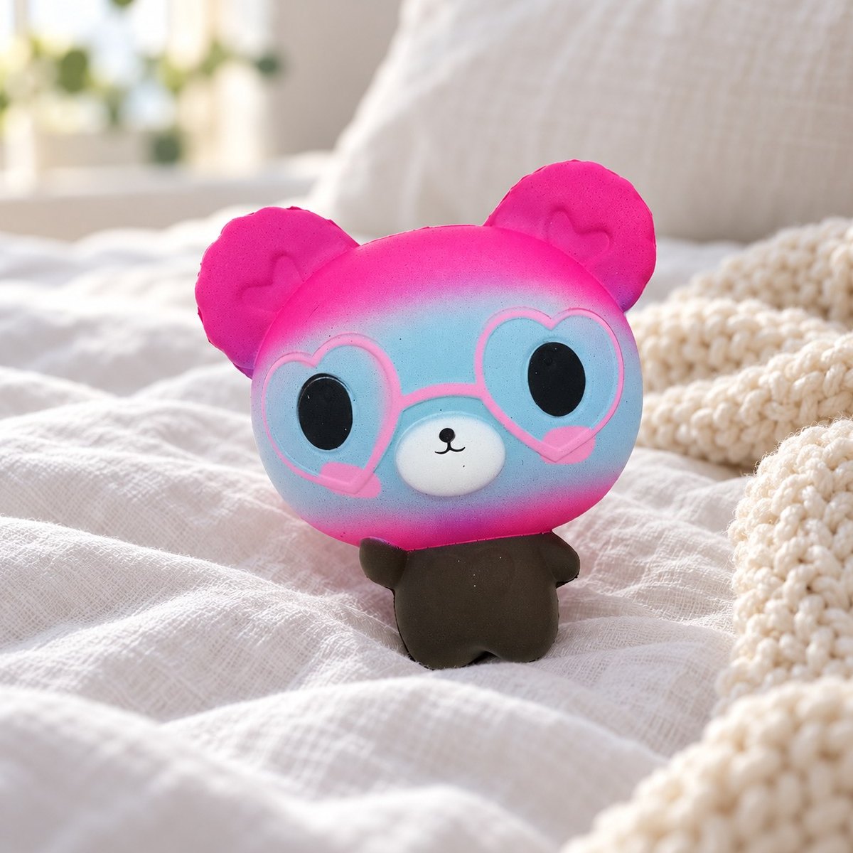 Björn squishy i rosa och blått på en mysig säng med mjuka filtar