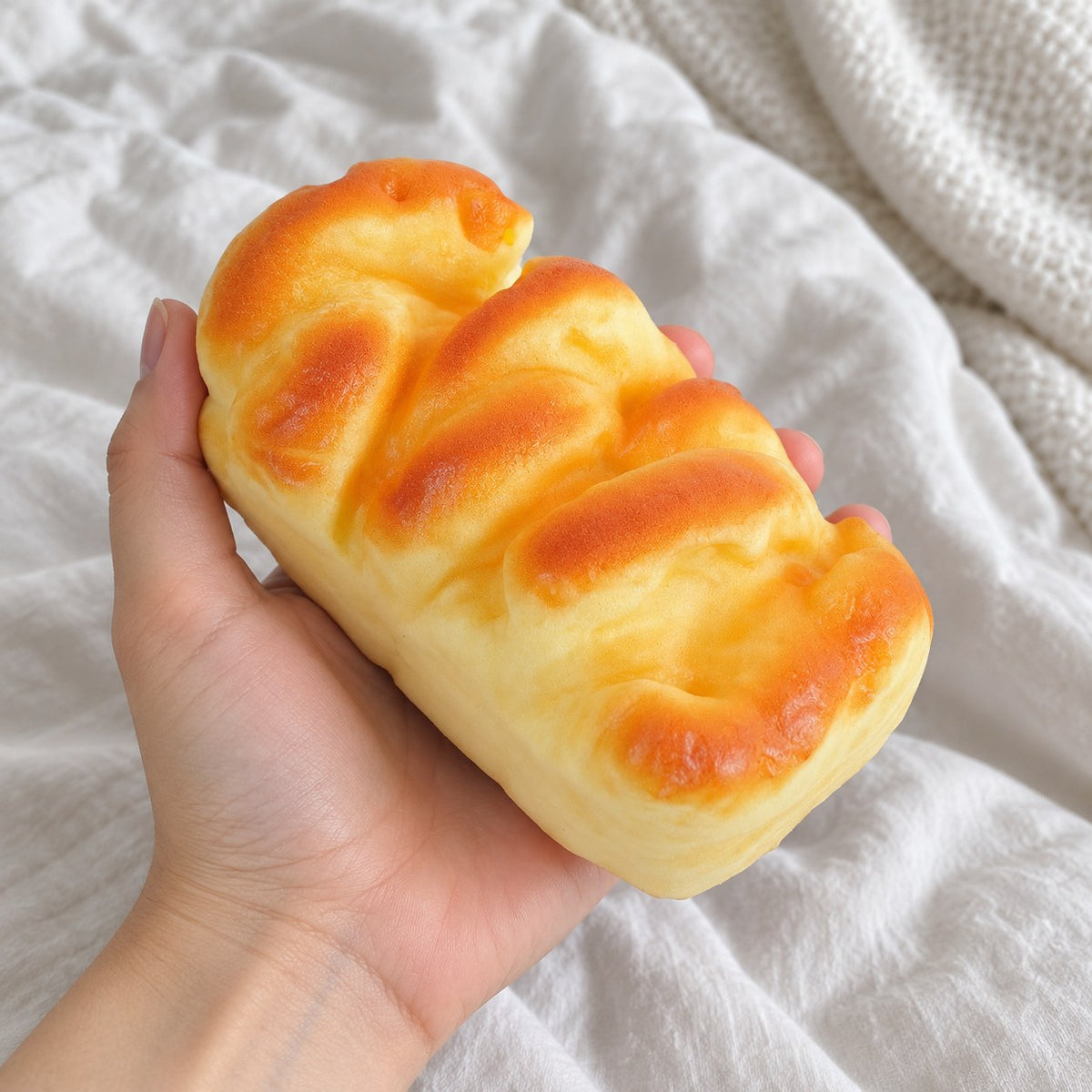 Brioche squishy slow rising (11 cm), held toward the camera, first-person view