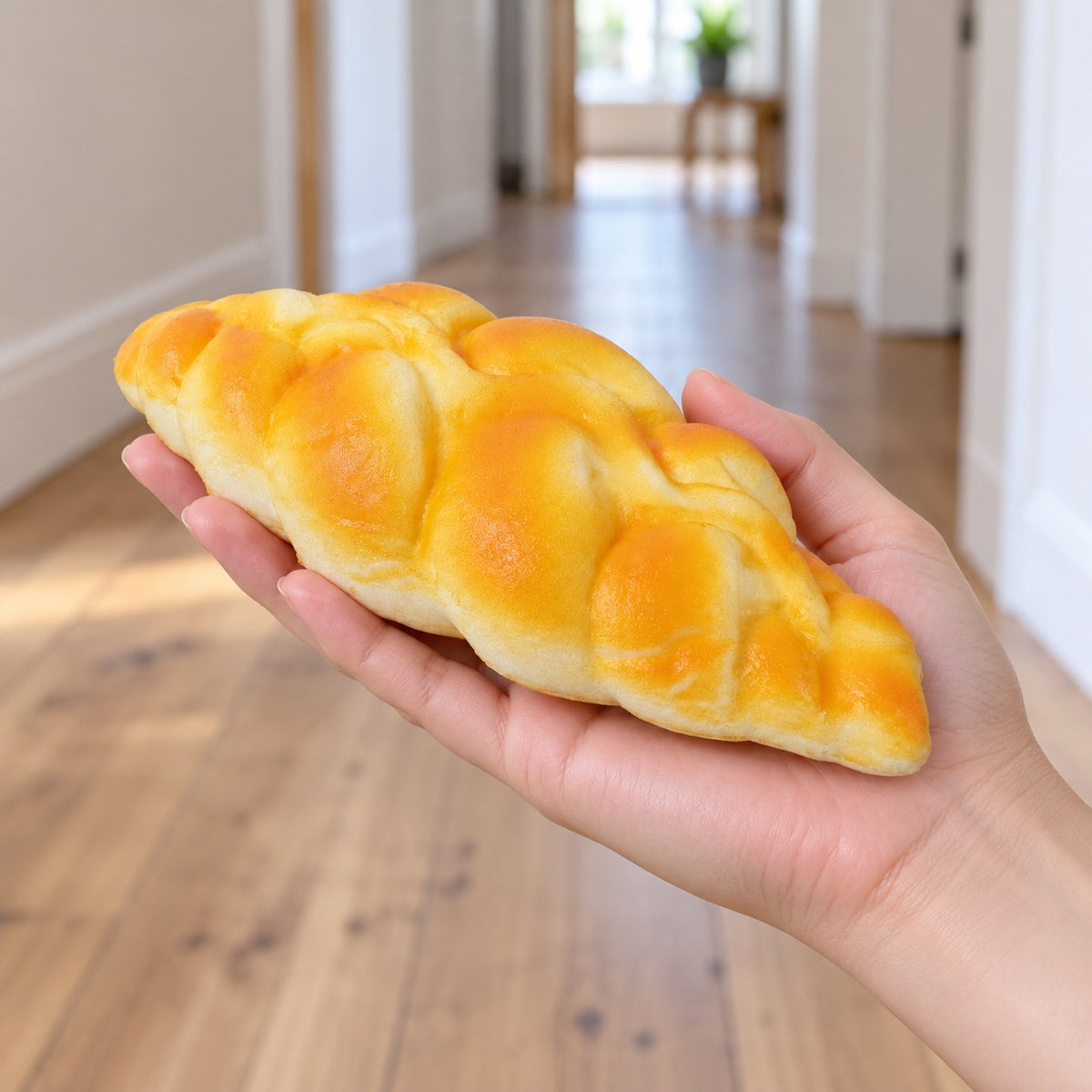 Braided bread squishy, held in a hand to show the real size