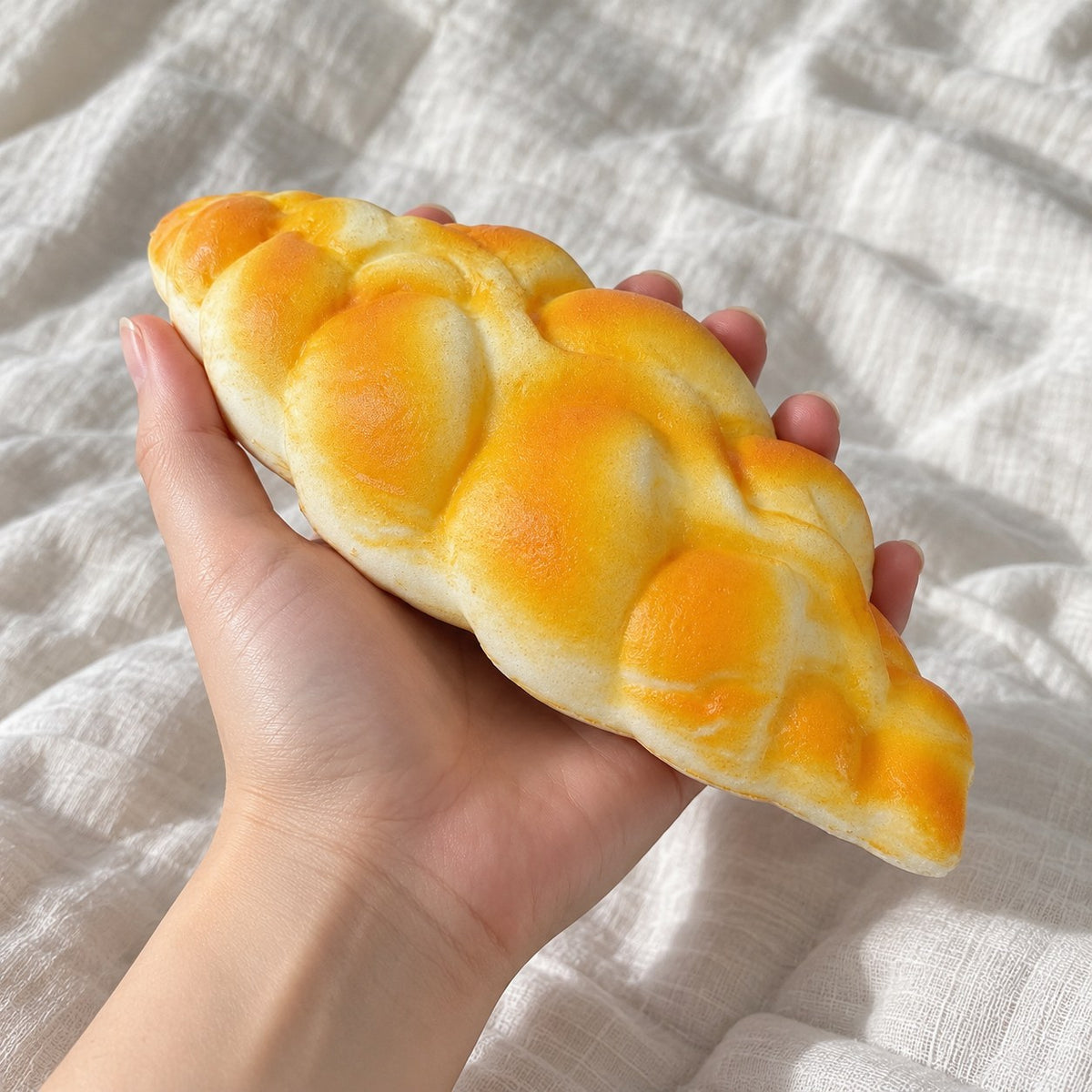 Braided bread squishy, held toward the camera, first-person view