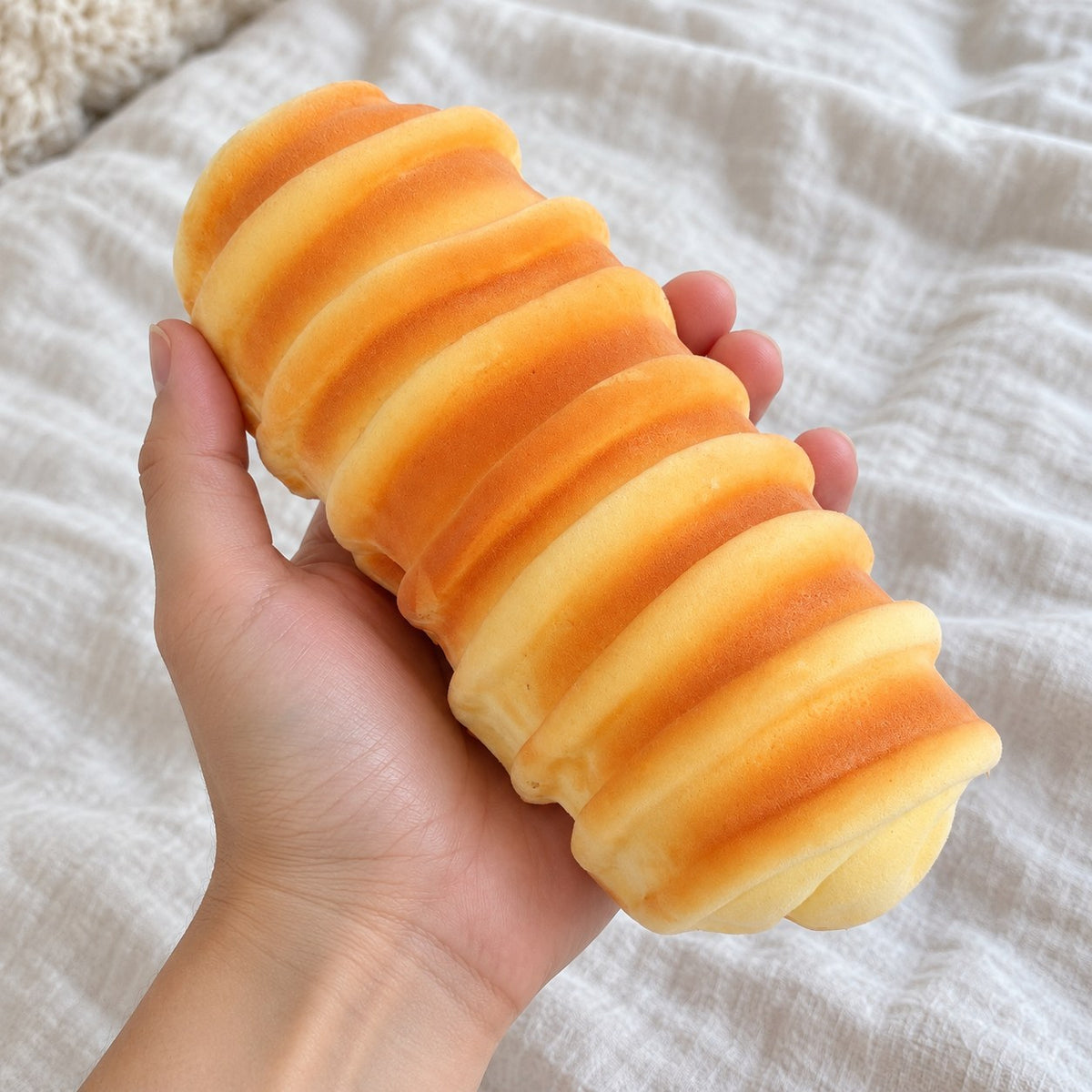 Caterpillar bread squishy slow rising (15 cm), held toward the camera, first-person view