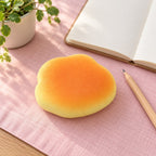 Cloud bun squishy, on a desk with a notebook and pencil