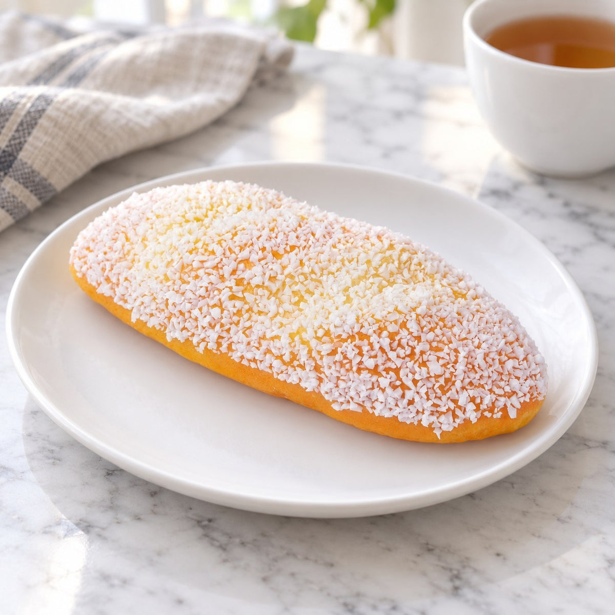 Coconut Cream Bun Squishy, 12 or 18 cm, on a plate on a breakfast table