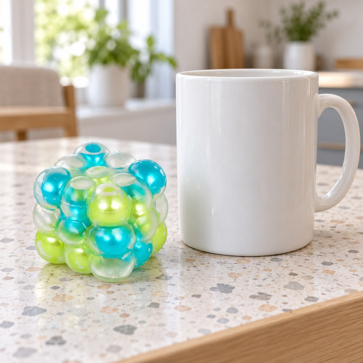 Bubble Cube Squishy, Pearl Balls Inside, 6 cm (Blue-green mix), next to a coffee mug for size comparison
