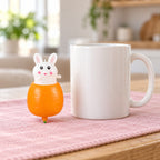 Bunny Pop-Up Squishy, Rabbit in a Carrot, next to a coffee mug for size comparison