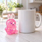Squishy lapin à paillettes, style sugar, à côté d'une tasse à café pour comparer la taille