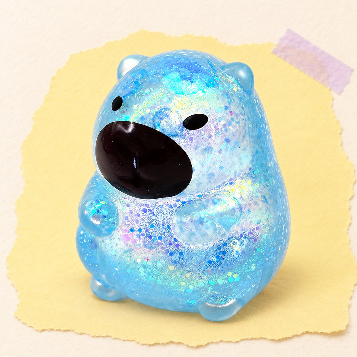 Blauwe capibara squishy met glitter in sugar-stijl op pastelkleurig papier