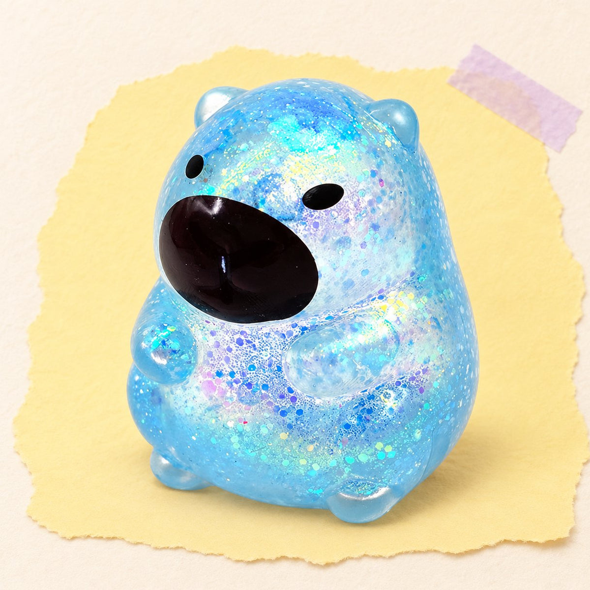 Capybara Squishy mit Glitzer in Blau, Sugar-Füllung, Produktfoto auf Pastellpapier