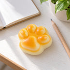 Cat paw bread squishy, on a desk with a notebook and pencil