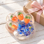 Cat paw squishy glitter jelly (Orange with blue glitter), as a small gift next to a wrapped box