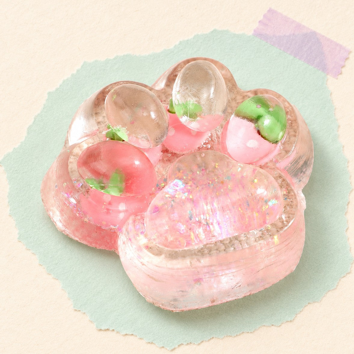 Cat paw squishy glitter jelly – Cat Paw Squishy with Fruit and Glitter, 7 cm (Strawberry pink), product photo on pastel paper