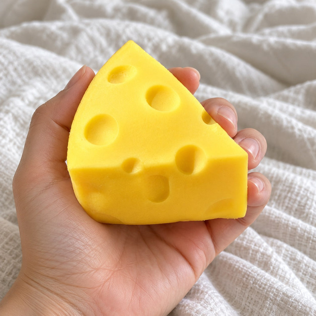Cheese wedge squishy soft, held toward the camera, first-person view