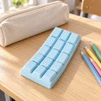 Chocolate Bar Squishy, Slow Rising 15.5 cm (Blue), on a school desk next to a pencil case