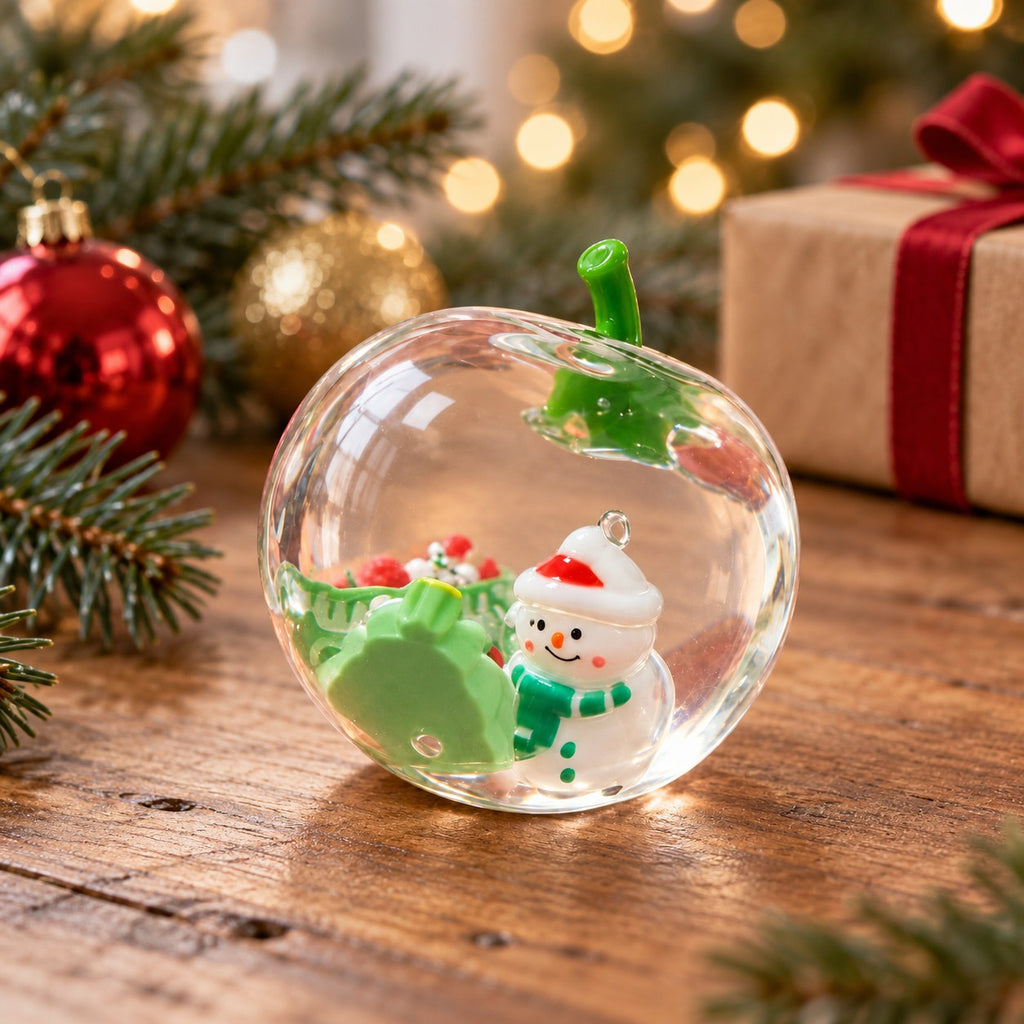 Squishy manzana navideña, transparente con muñeco de nieve, en una escena navideña con ramas de abeto y luces
