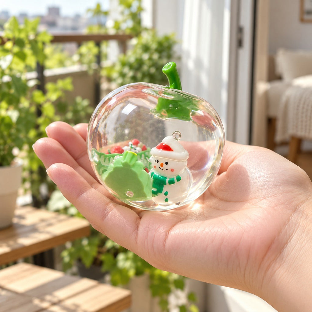 Squishy manzana navideña, transparente con muñeco de nieve, en la mano para ver su tamaño real