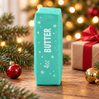 Christmas Butter Squishy, Crispy Stick in Gift Box (mint green), in a Christmas scene with fir branches and fairy lights