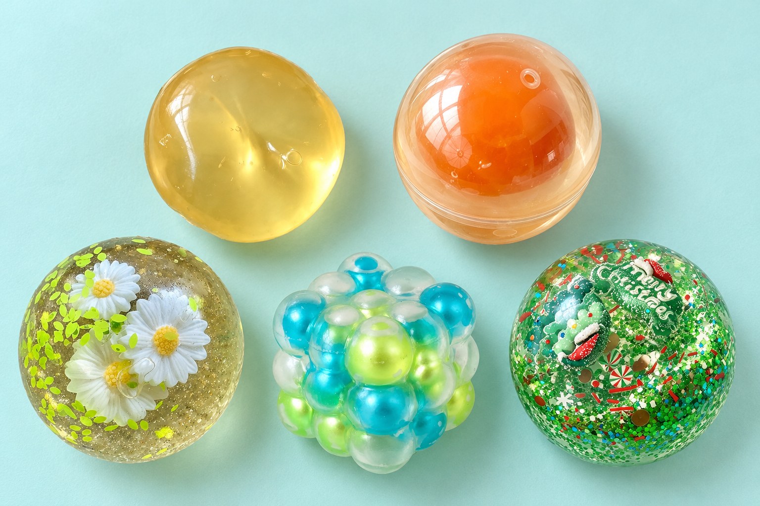 Coconut oil squishies set ovenfra på turkis: frugtbold, æggeblommebold, maltosebold, bobleterning og julekugle