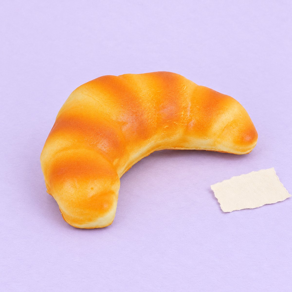 Slow rising croissant squishy, realistiskt bröd på 12,5 cm, på pastellpapper