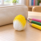 Crunchy Cabbage Squishy, Handmade (Yellow), on a school desk next to a pencil case