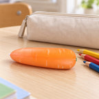 Crunchy Carrot Squishy, Crispy PU Vegetable, on a school desk next to a pencil case