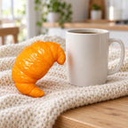 Crunchy Croissant Squishy, Handmade, next to a coffee mug for size comparison