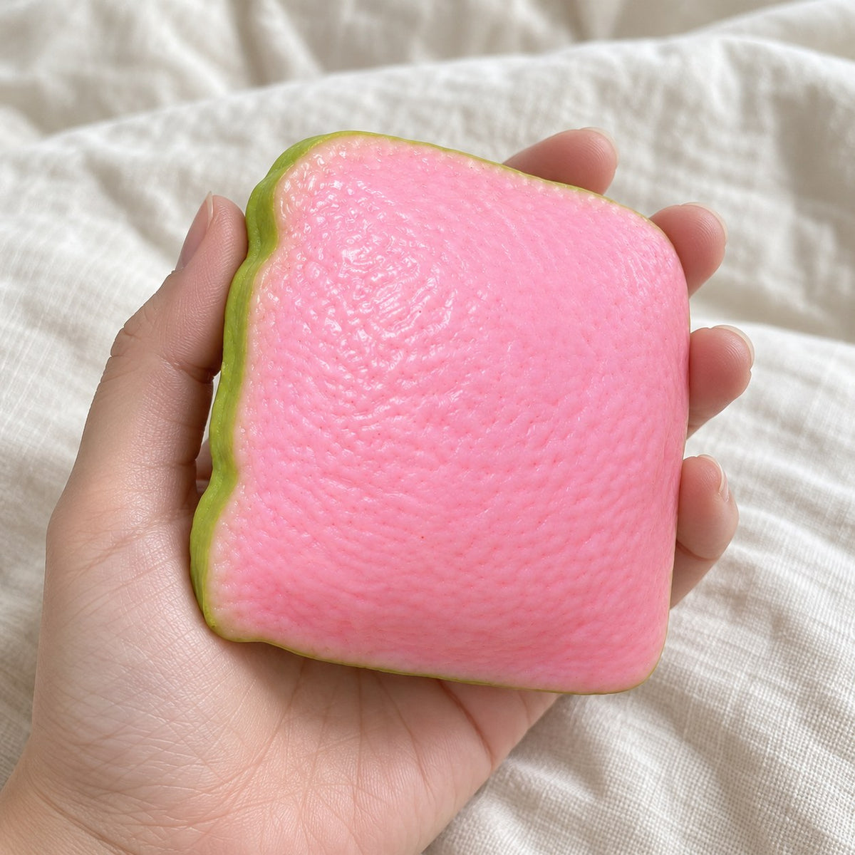 Crunchy Guava Squishy, Pink Slice, held toward the camera, first-person view