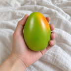 Mango squishy crunchy, held toward the camera, first-person view