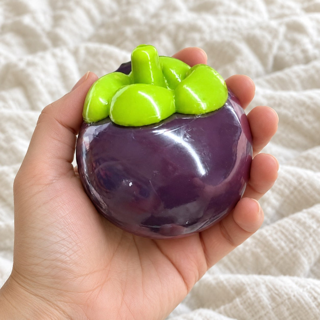 Mangosteen squishy, held toward the camera, first-person view
