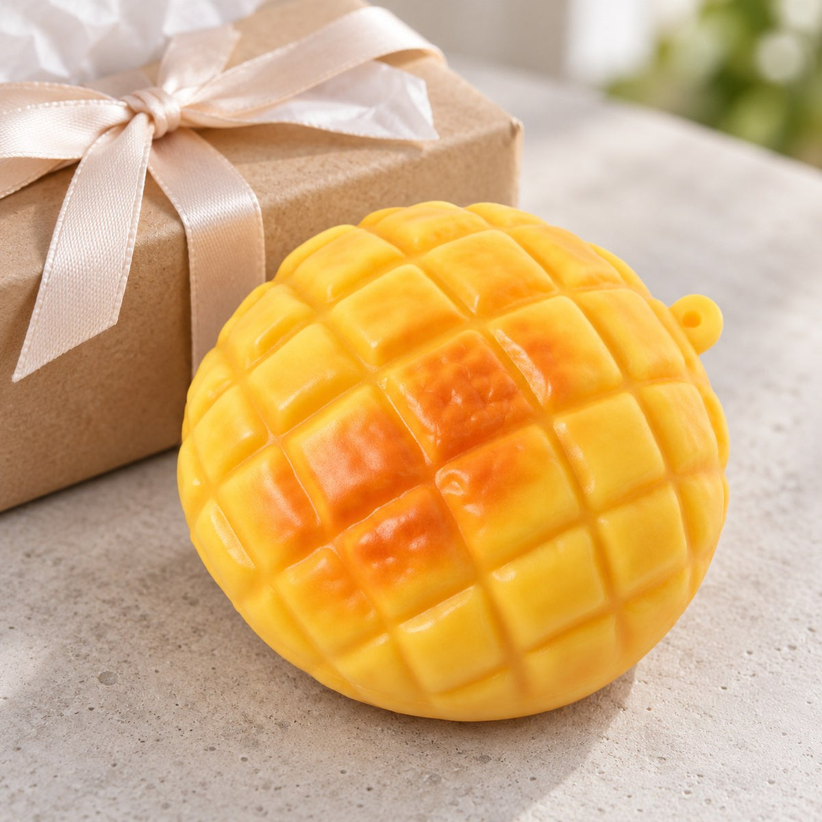 Pineapple bun squishy crunchy, as a small gift next to a wrapped box