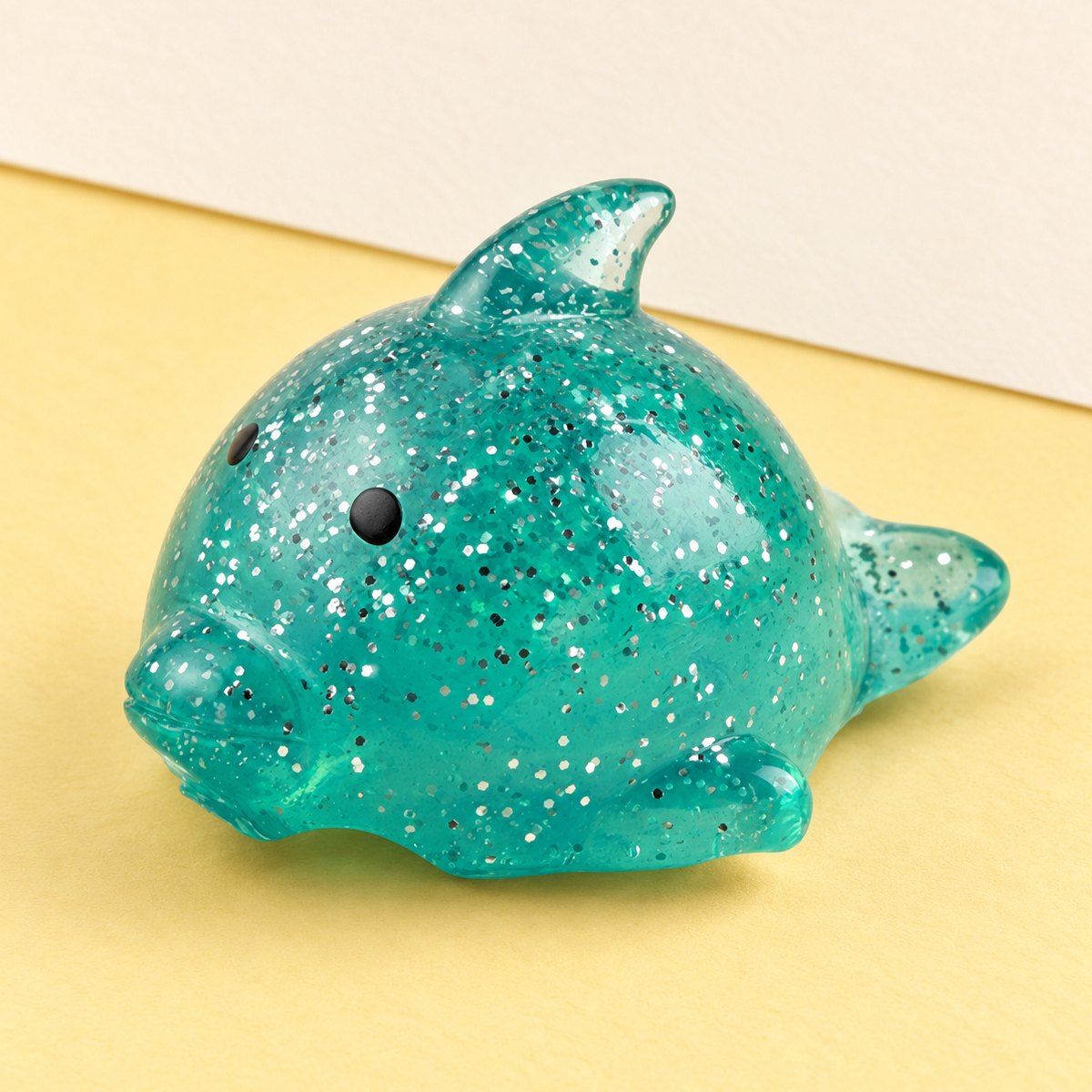 Stor mochi delfin squishy med glitter på pastellfärgat papper