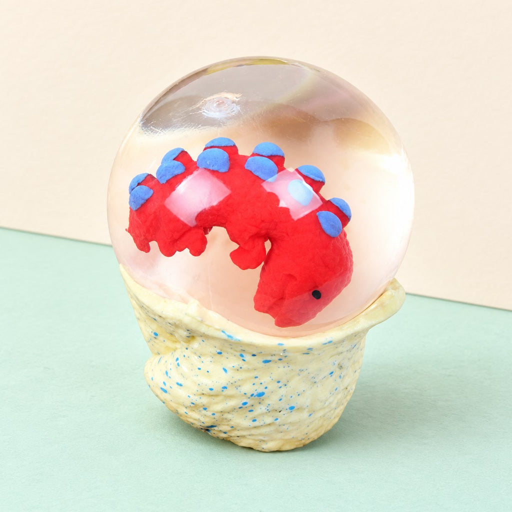 Dino-Ei Squishy als Wasserball mit Baby-Dino, auf Pastellpapier