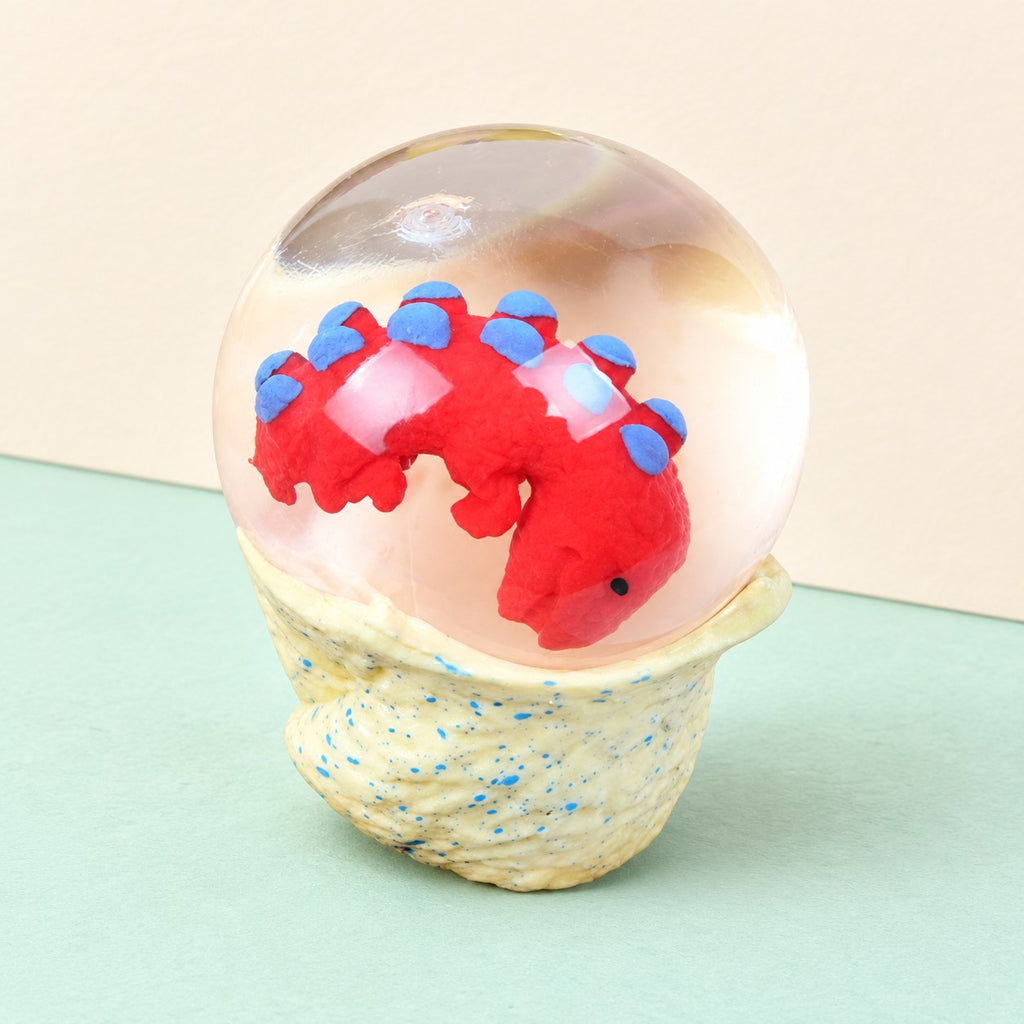 Dinosaur egg squishy water ball with baby dino, product photo on pastel paper