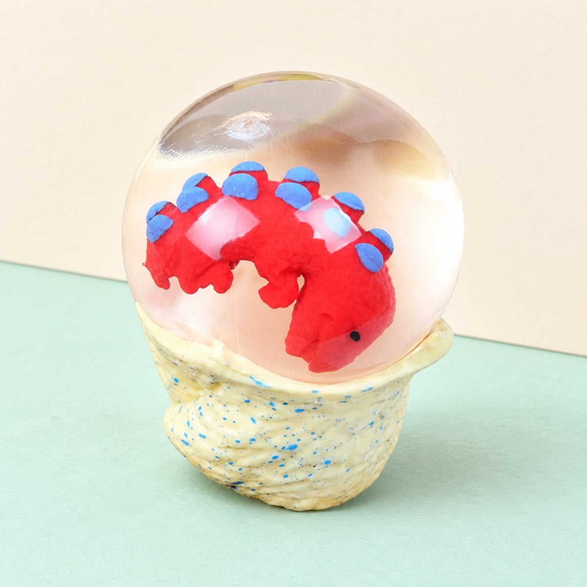 Dinosaur egg squishy water ball with baby dino, product photo on pastel paper