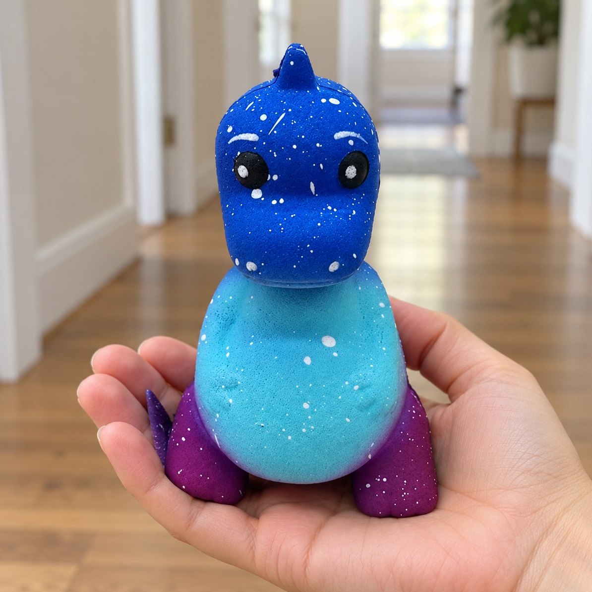 Dinosaur squishy i blå galakse holdt i hånden, så man ser den rigtige størrelse