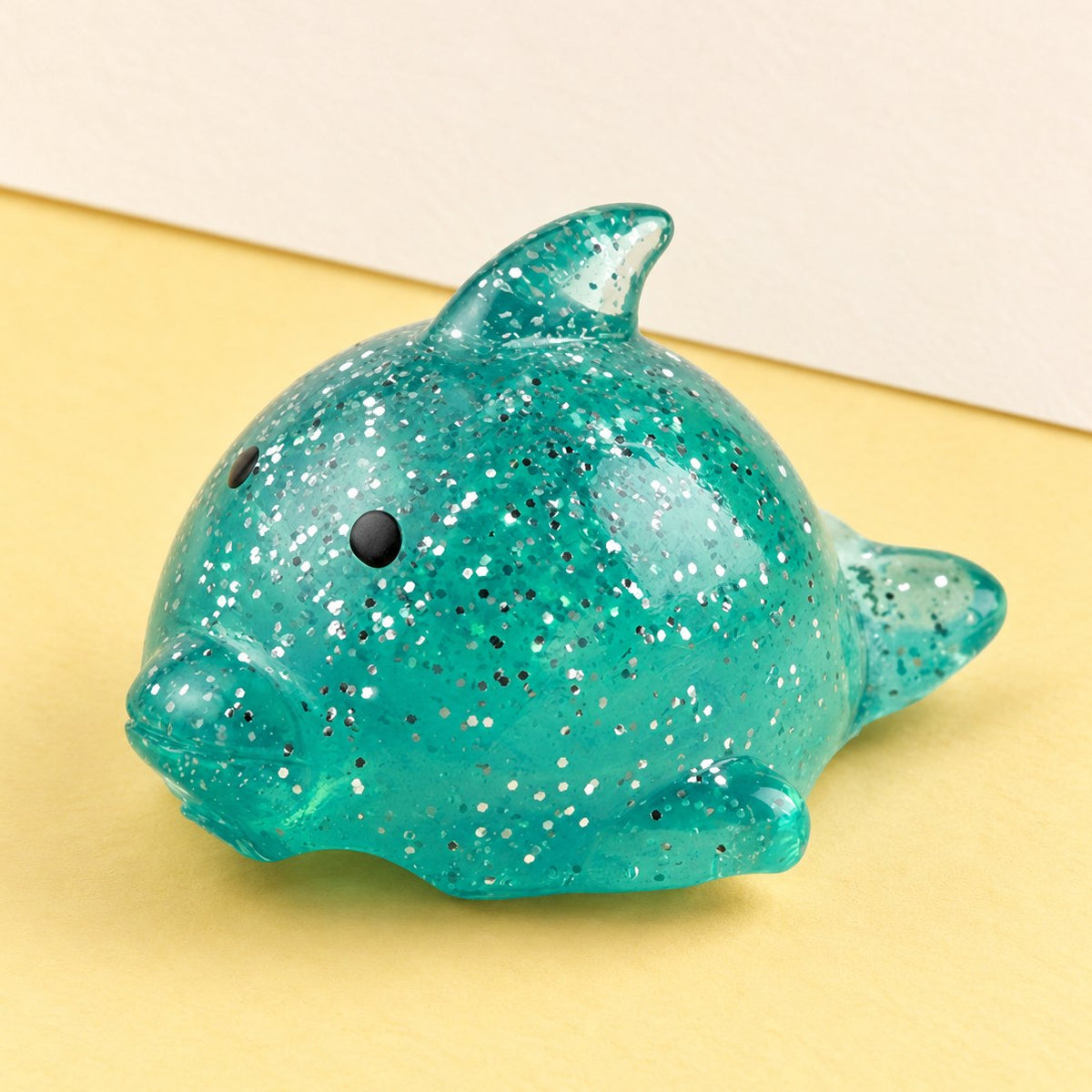 Dolfijn squishy, groot en met glitter, op pastelkleurig papier