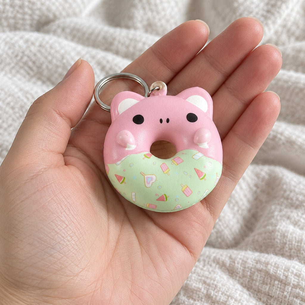 Squishy přívěsek donut se zvířecím obličejem, slow rising, držený směrem k fotoaparátu z pohledu první osoby