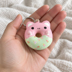 Squishy přívěsek donut se zvířecím obličejem, slow rising, držený směrem k fotoaparátu z pohledu první osoby