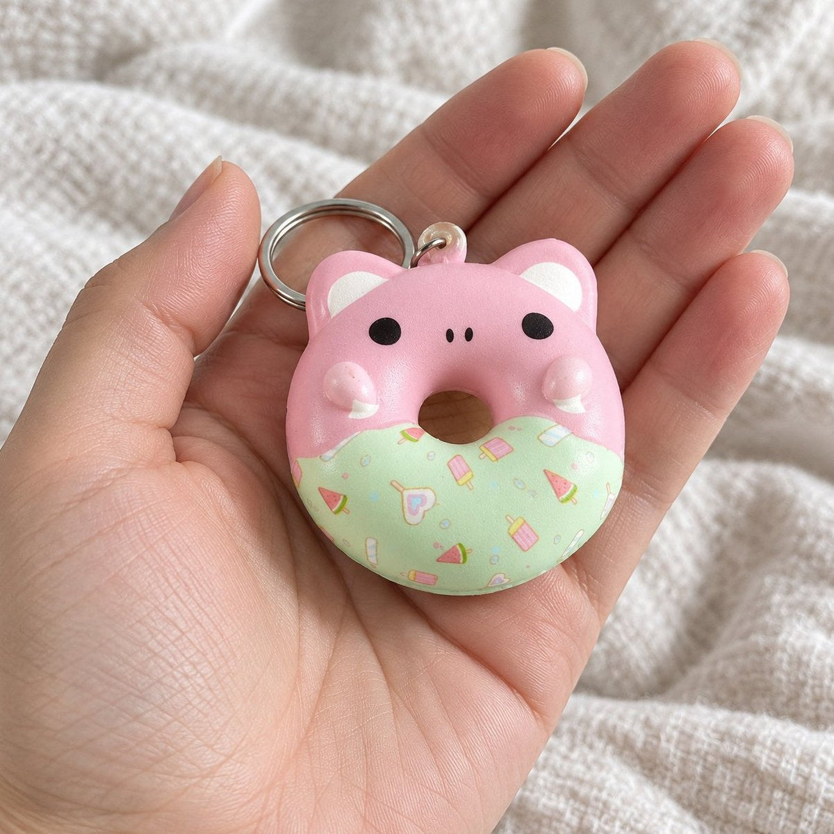 Vanuit eigen perspectief: donut squishy sleutelhanger met dierengezichtje naar de camera gehouden