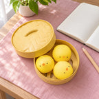 Chick Bao Squishy, 3 Buns in Steamer Basket, on a desk with a notebook and pencil